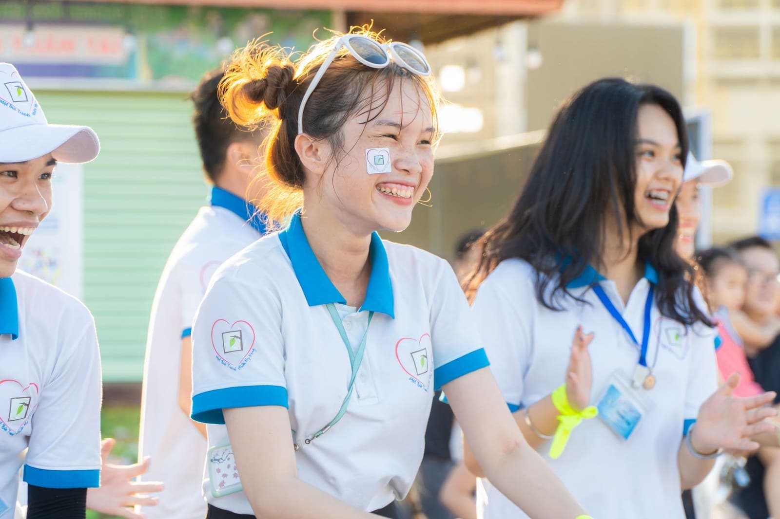 Young volunteers in matching shirts smiling at an outdoor event