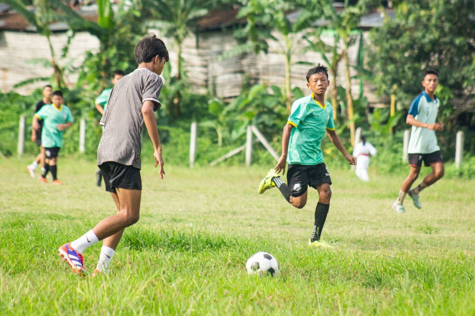 Teenagers playing football on a grassy field