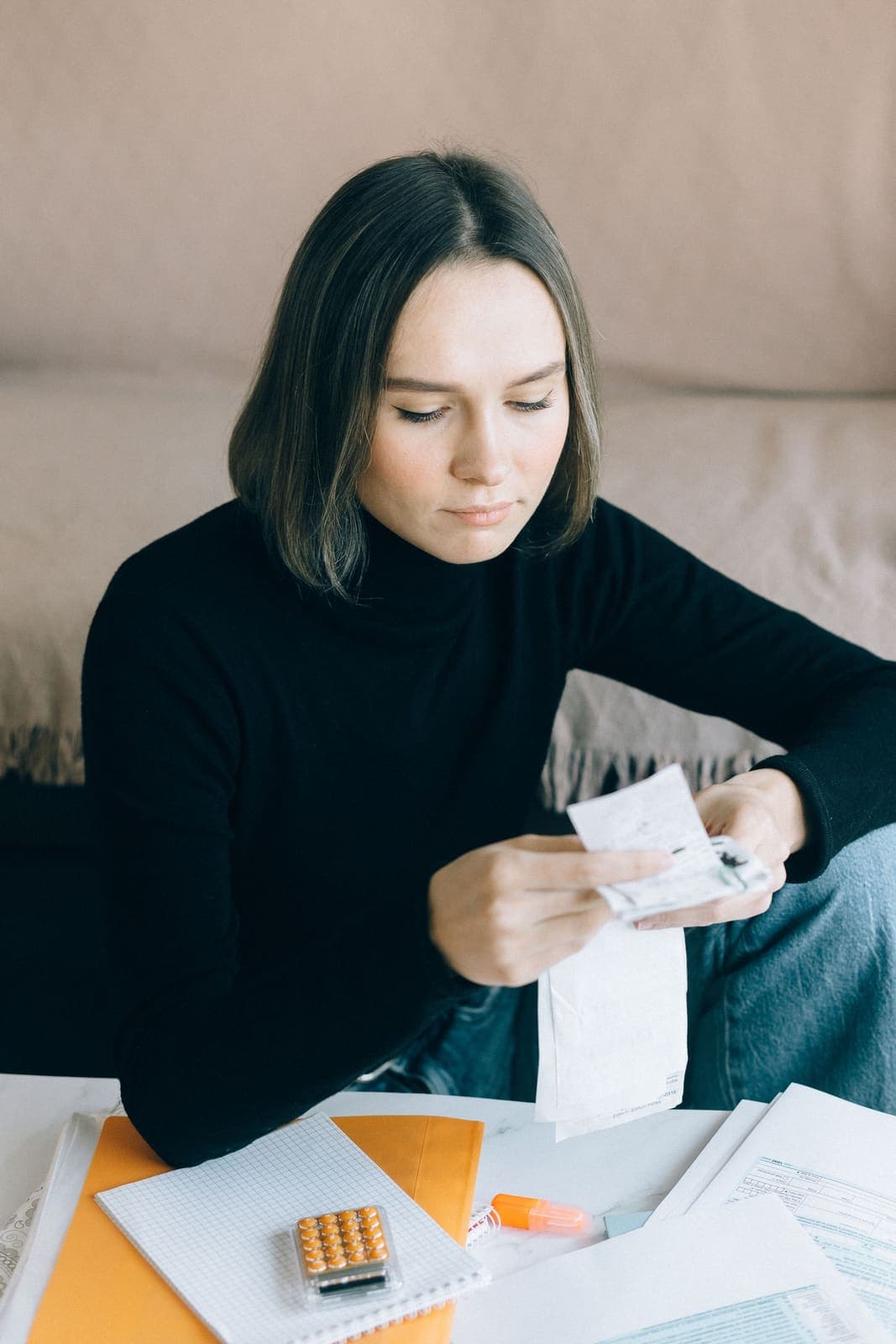 A young woman reviewing bills at home with a calculator