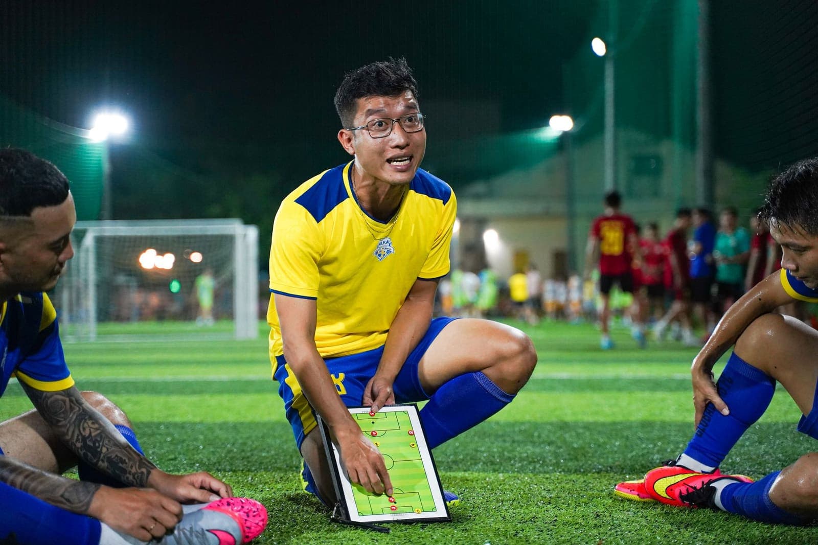 A football coach crouching with players around a tactics board