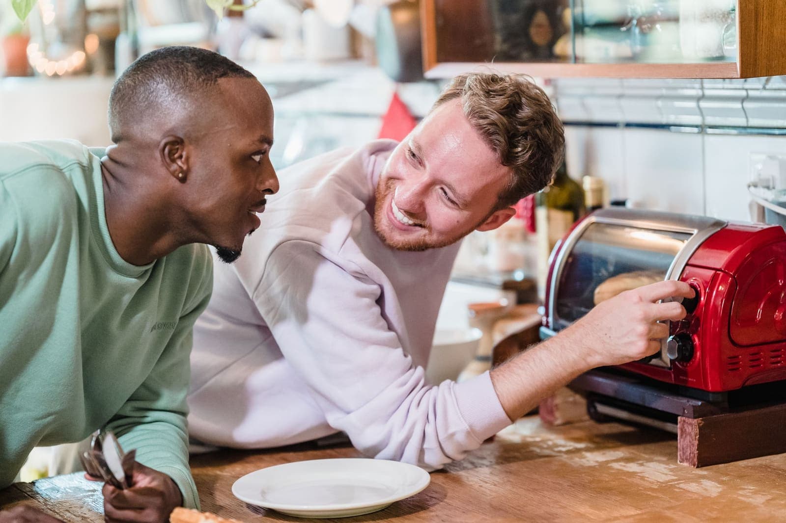 Two young men laughing while making breakfast in a kitchen