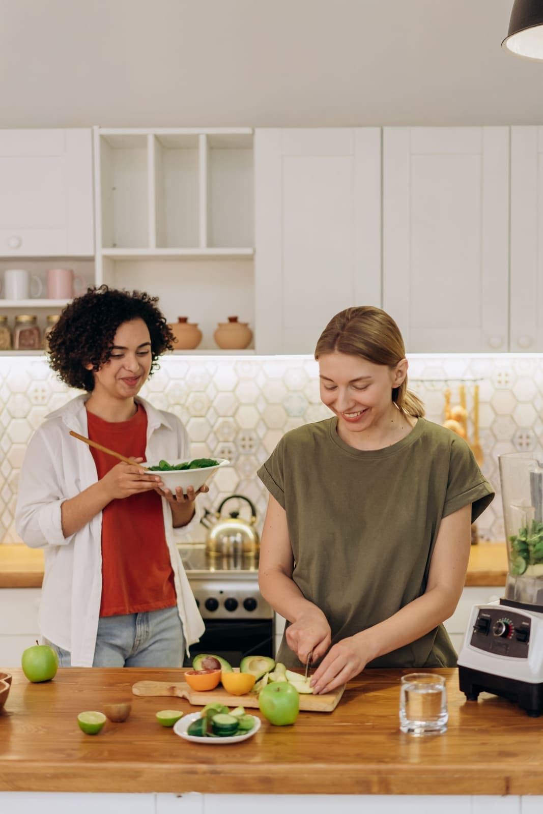 Two young women cooking with fresh vegetables in a bright kitchen