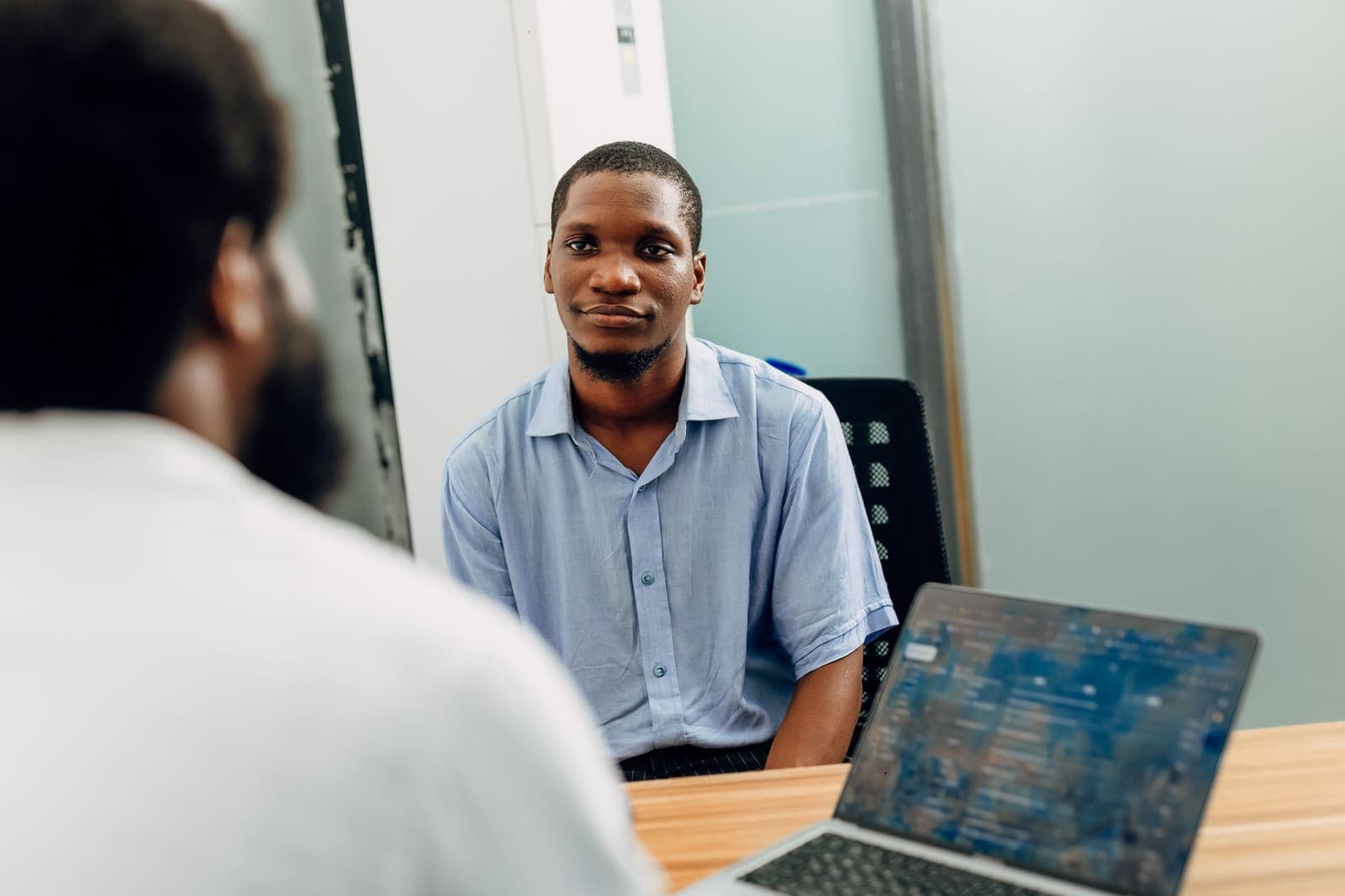 A young man smiling across a table during an interview