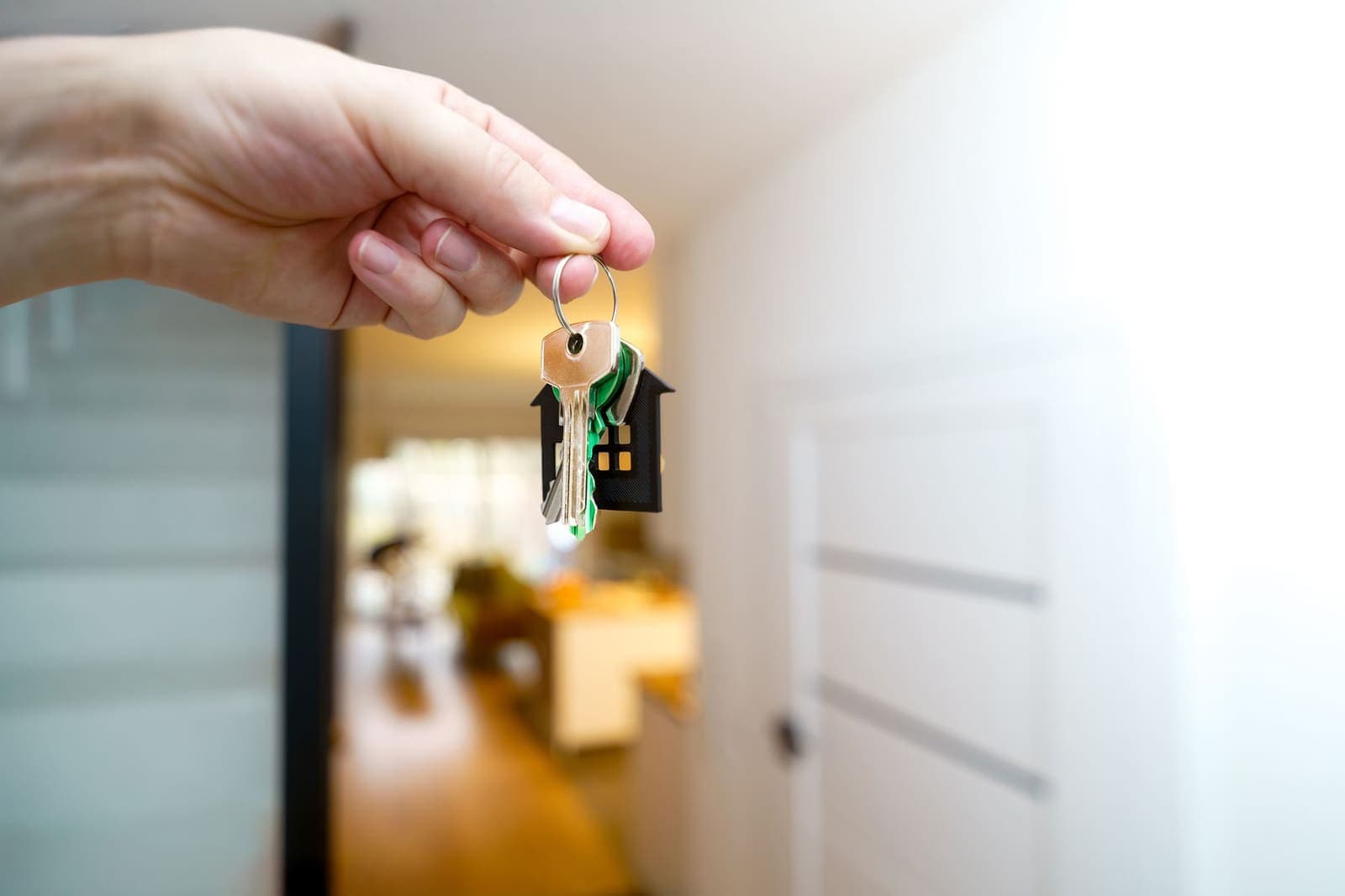 A hand holding house keys inside a bright, modern flat