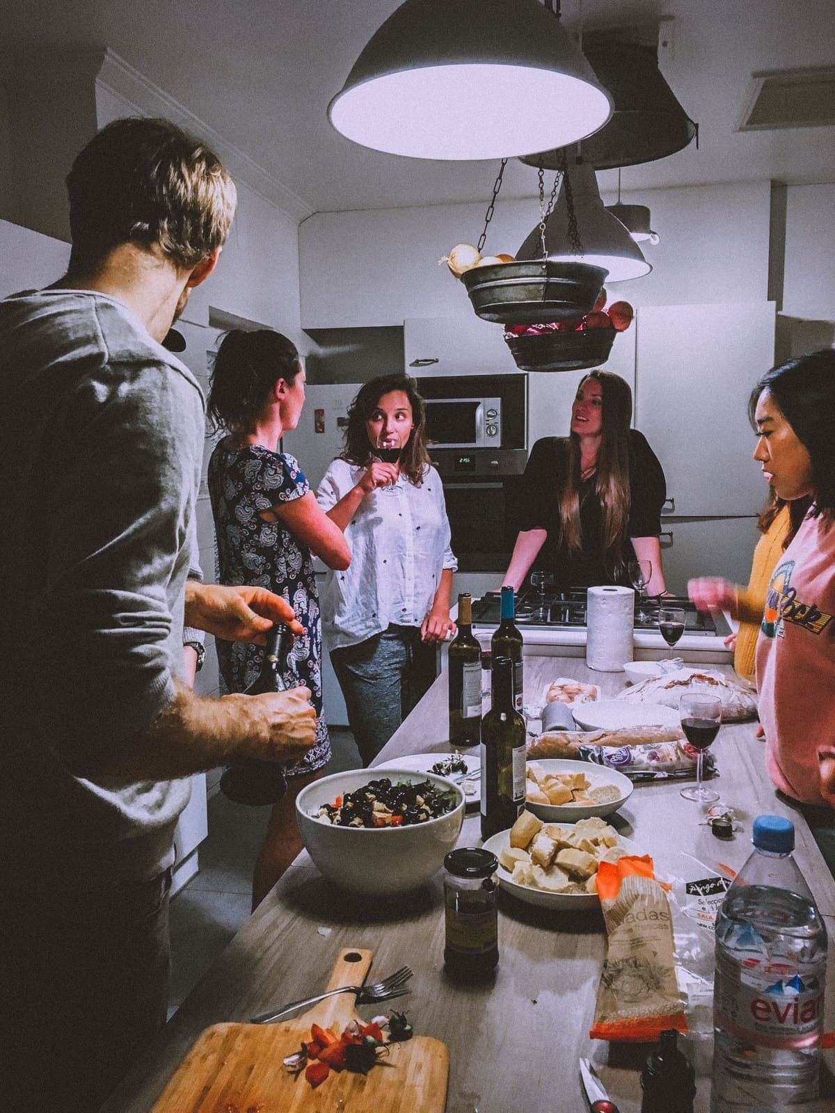 A group of young adults cooking and talking in a kitchen