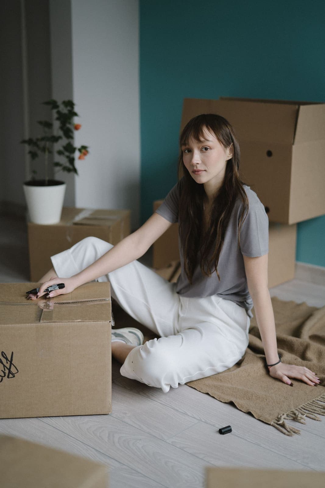 A young woman sitting among moving boxes in her new home