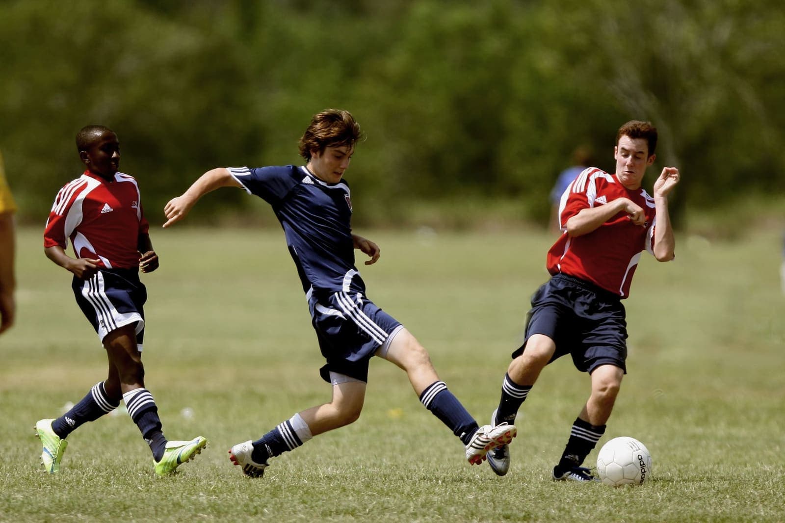 Teenage footballers playing a match on a grass pitch