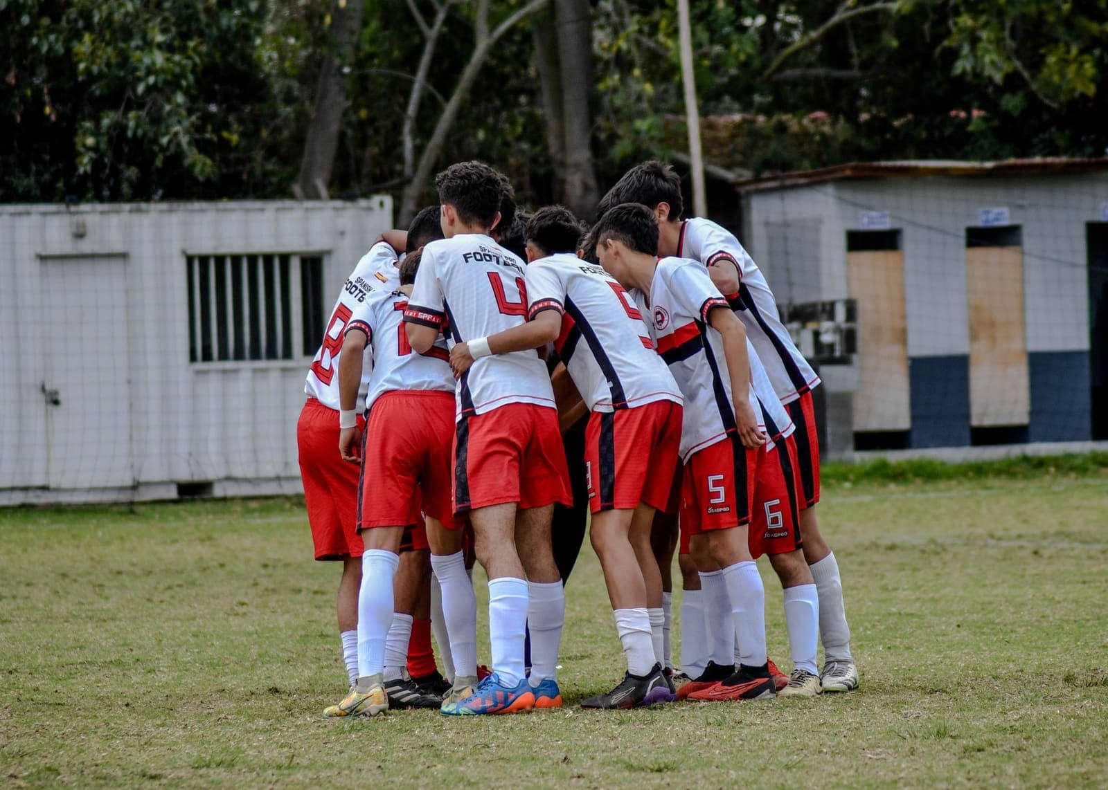 Young football players in matching kit huddled on a pitch