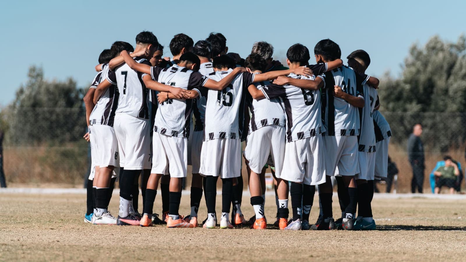 A youth team in matching shirts huddled on the field